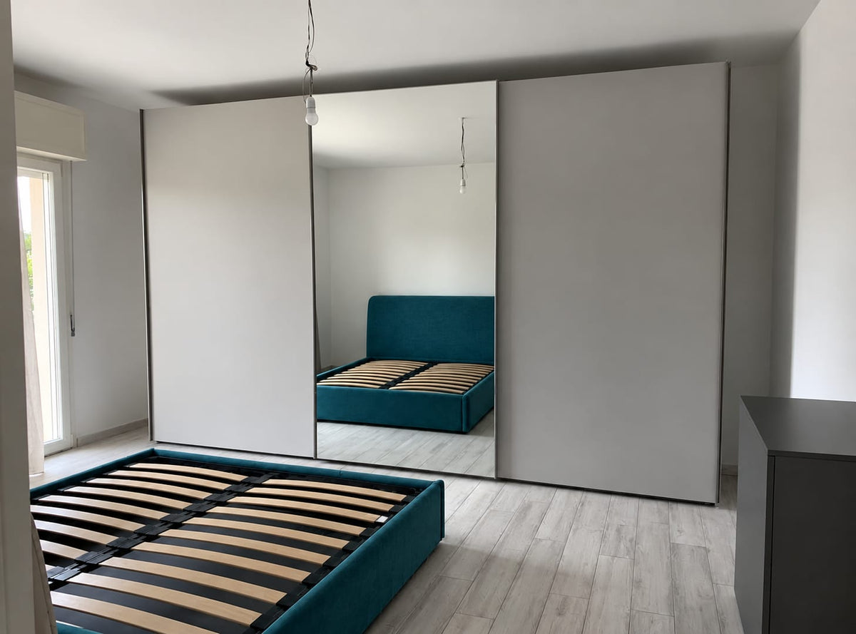 Camera matrimoniale moderna con armadio ad ante scorrevoli, letto petrolio e comò