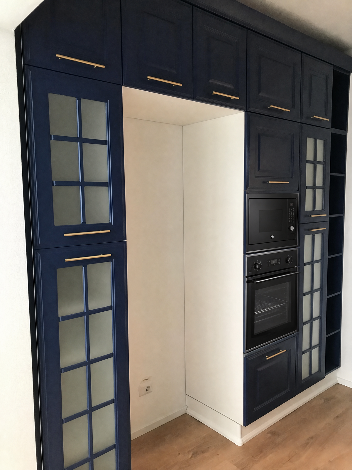 Composizione cucina classica con anta telaio laccata opaca blu, zoccoli in legno bianco e maniglie metallo champagne